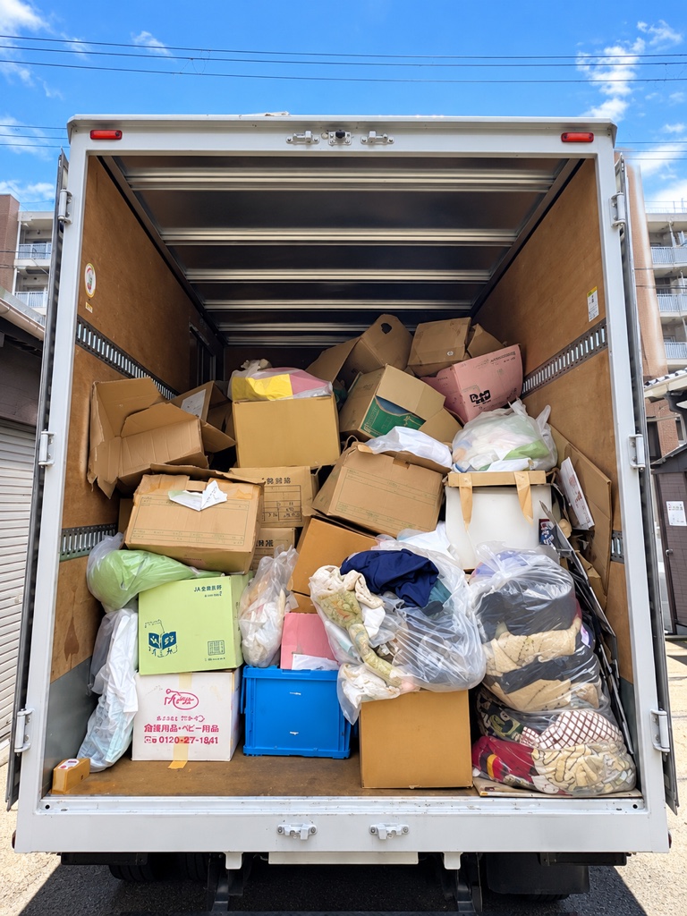 段ボールや袋詰めの荷物を荷台いっぱいに積み込んだトラック